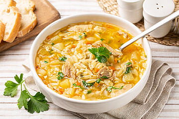Homemade Chicken Orzo Soup In A White Plate, Fresh Bread.